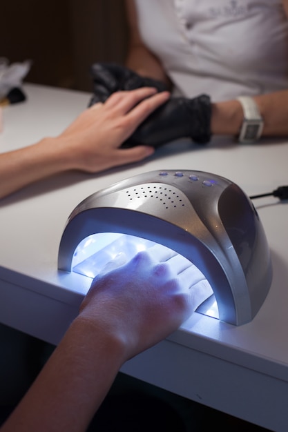 Meisje droogt nagellak in een UV-lamp.