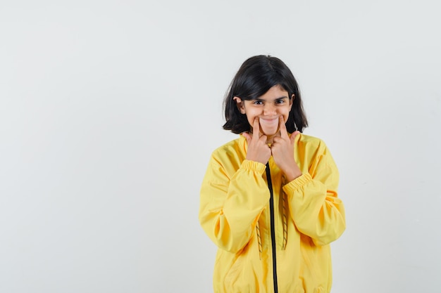 Meisje dwingt een glimlach op gezicht in geel hoodie vooraanzicht.