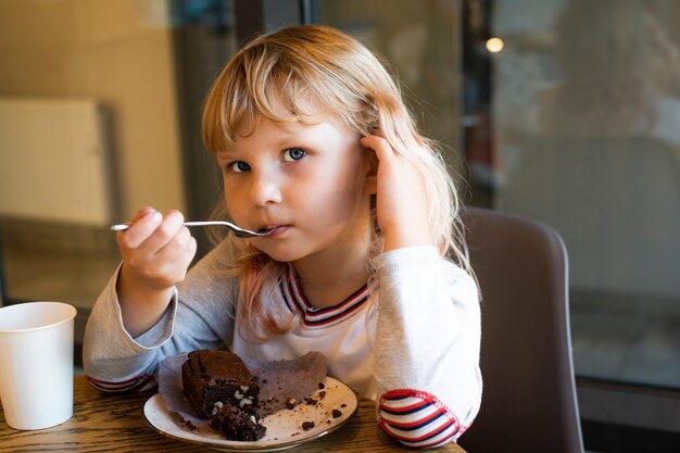 meisje eet chocoladetaart als toetje in een café