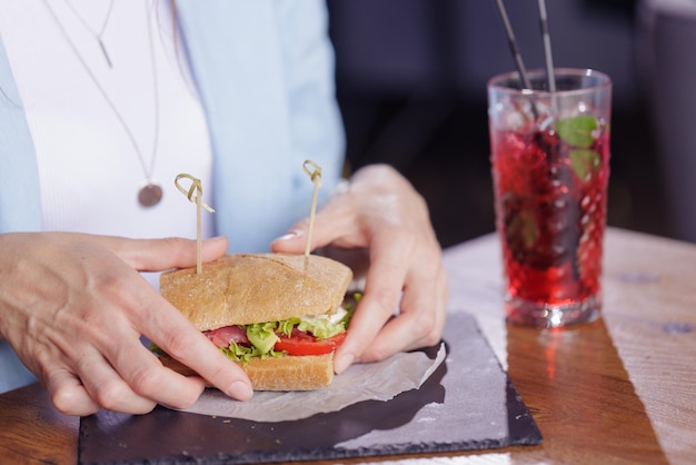 Meisje eet heerlijke sandwich close-up in modern café