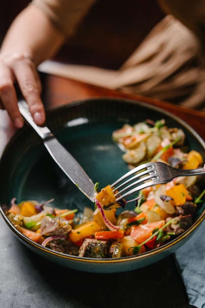 Meisje eet salade met gestoofde kalfswangetjes, aardappelpartjes, tomaten en mosterdsaus