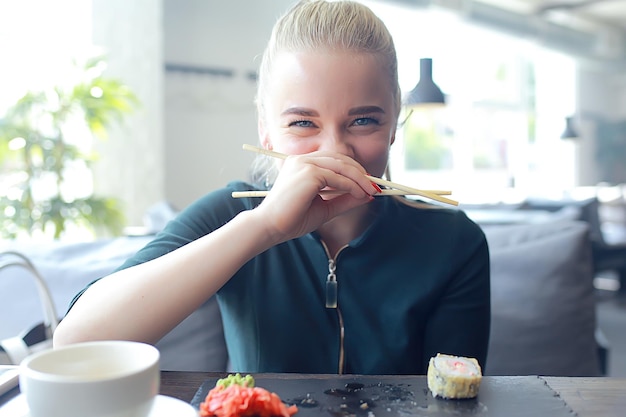 Meisje eet sushi en rolt in een restaurant / oosterse keuken, japans eten, jong model in een restaurant