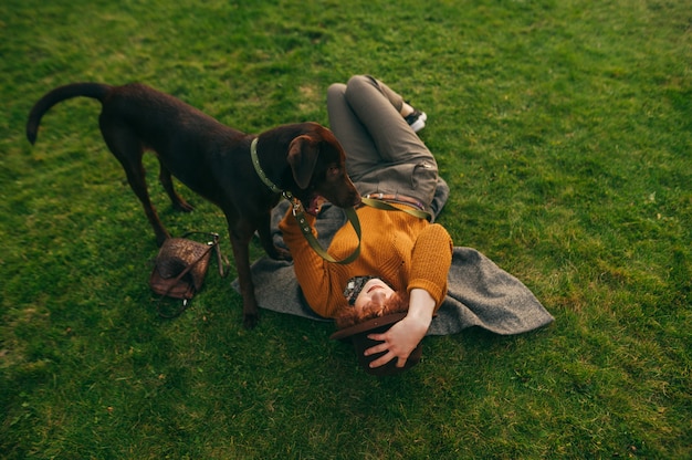 Meisje eigenaar en hond op gazon, stijlvolle dame liggend op het gras en puppy aan de leiband te houden