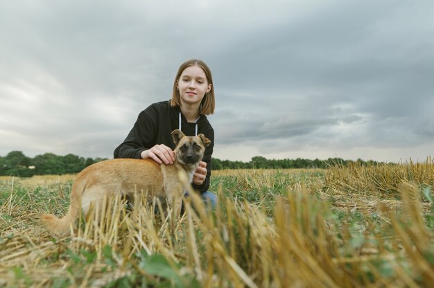 Meisje eigenaar met kleine bastaard hond zittend op het veld