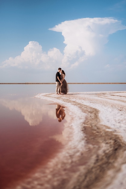Meisje en een jongen aan de oever van een roze zoutmeer bij zonsondergang
