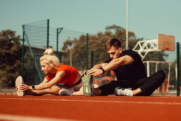 Meisje en een jongen doen een warming-up voor sportoefeningen in het schoolstadion