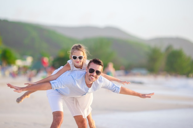 Meisje en gelukkige papa die pret hebben tijdens strandvakantie