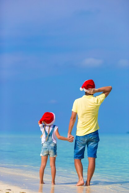 Meisje en gelukkige papa in Santa Hat tijdens strandvakantie