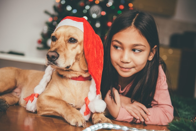 Meisje en hond die door de Kerstmisboom bepalen