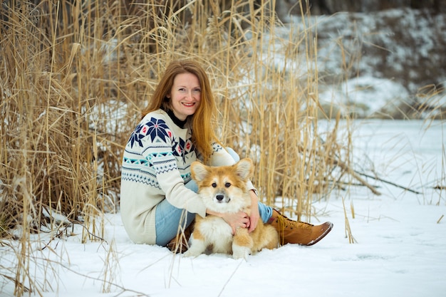 Meisje en kleine schattige corgi pluizige puppy in de buitenlucht. winter