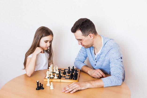 Meisje en vader spelen thuis een spelletje, schaken, puzzelen voor hersenontwikkeling, mentale intelligentie