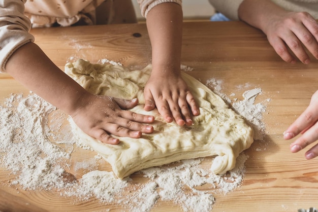 Meisje en vrouw koken thuis in een keuken een kind roert meel kneed het deeg op tafel met de hand