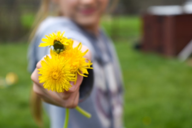 meisje geeft een boeket gele paardebloemen, bloemgift