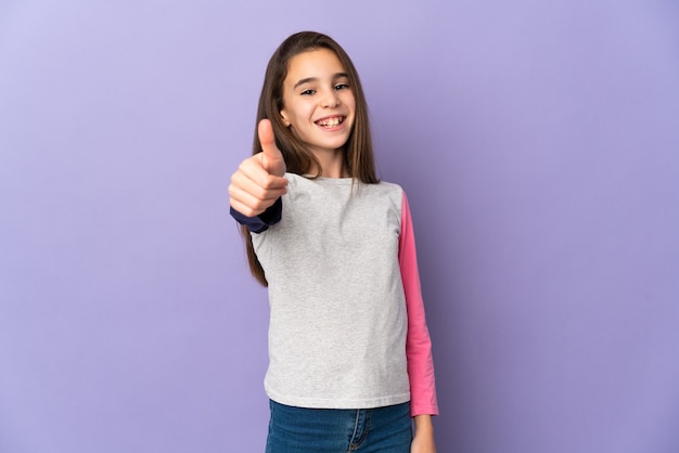 Meisje geïsoleerd op paarse achtergrond met thumbs up omdat er iets goeds is gebeurd