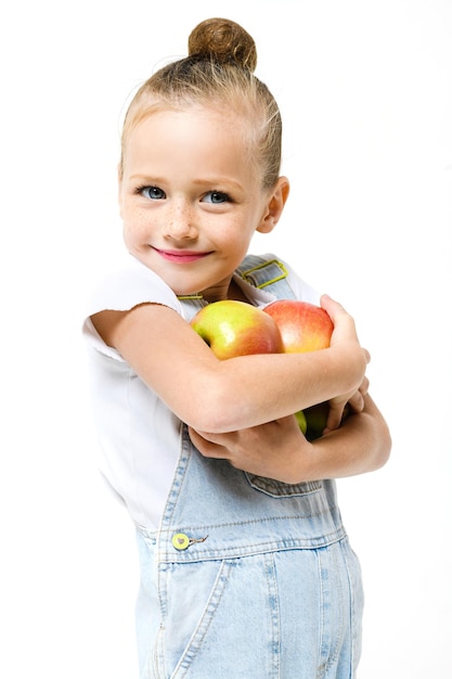 Meisje gekleed in denim overall met armvol appels op een witte achtergrond