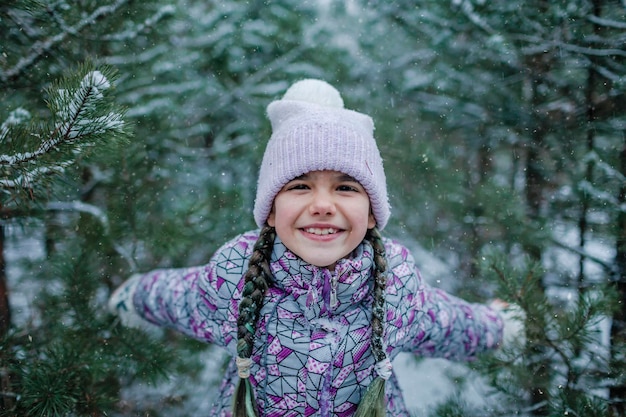 Meisje geniet van de eerste sneeuw tijdens familiewandelingen in het bos op sneeuwdag winter wonderland