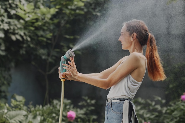 Meisje geniet van water in de hitte van de zomer in de tuin