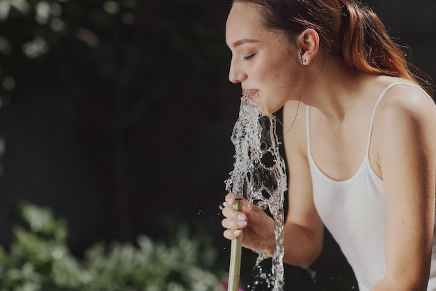 Meisje geniet van water in de hitte van de zomer in de tuin