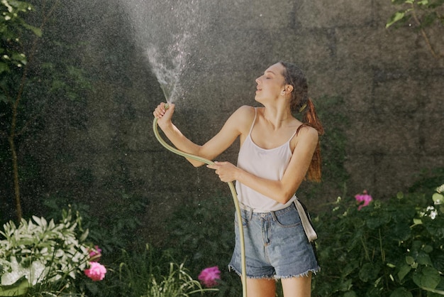Meisje geniet van water in de hitte van de zomer in de tuin