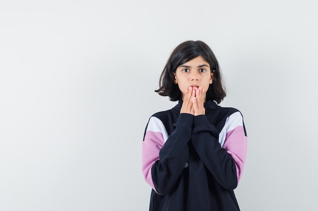 Meisje hand in hand op kin in shirt en op zoek angstig, vooraanzicht.