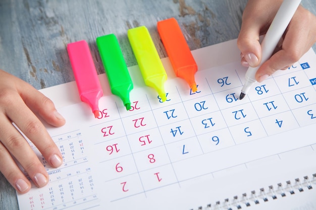 Foto meisje hand markeert kalender met een marker