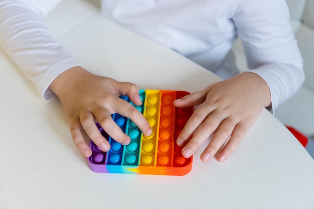 Meisje handen close-up spelen met regenboog pop it fidget het concept van popit toy voor geestelijke gezondheid