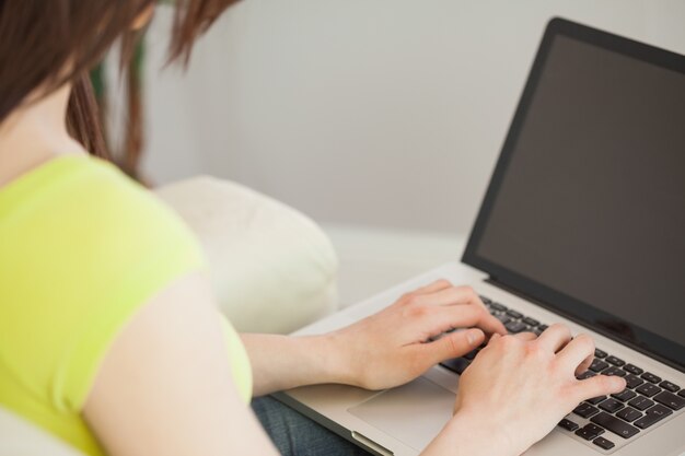 Meisje het typen op laptop zitting op een bank