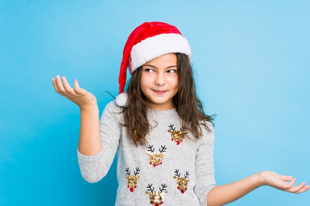 Meisje het vieren Kerstmisdag die en schouders in het vragen van gebaar twijfelen ophalen.