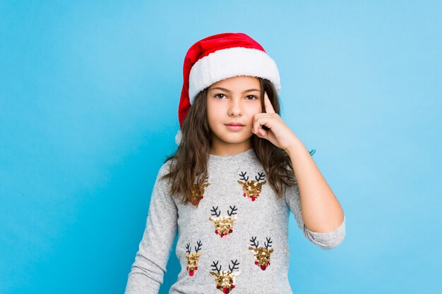 Meisje het vieren Kerstmisdag die tempel met vinger richten, denken, concentreerde zich op een taak.