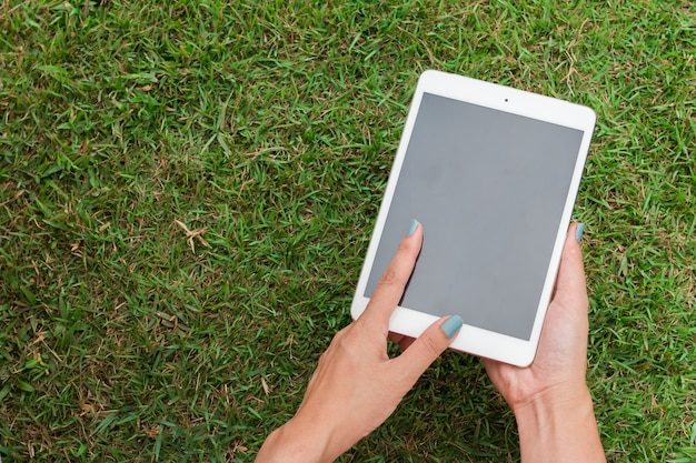 meisje houden en aanraken witte digitale tablet op groen glas achtergrond