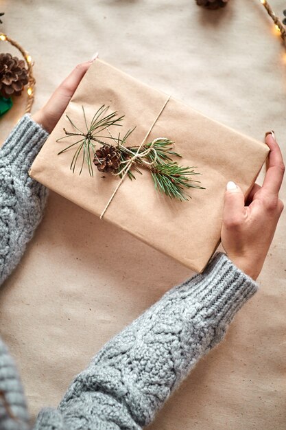 Meisje houdt cadeau verpakt in ambachtelijk papier. Vrouw maakt en verpakt kerstcadeautjes