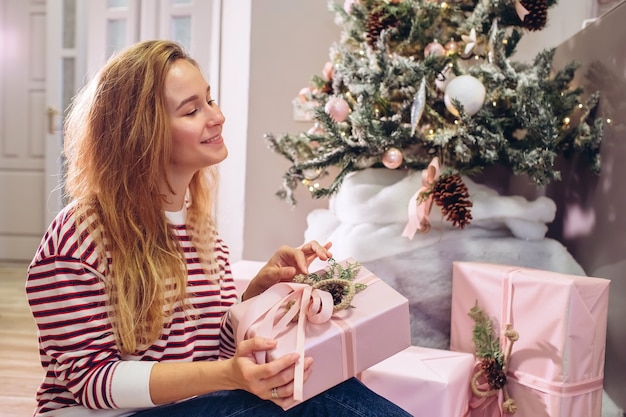 Meisje houdt een geschenk, kerstboom, roze doos met een geschenk