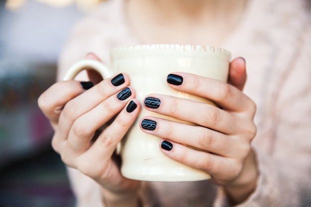 Meisje houdt een kopje koffie met mooie zwarte manicure. Kerstmis-