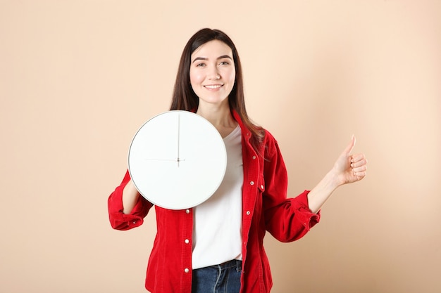 Meisje houdt een mechanische klok vast op een gekleurde achtergrond