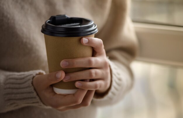 Meisje houdt een papieren beker met koffie.