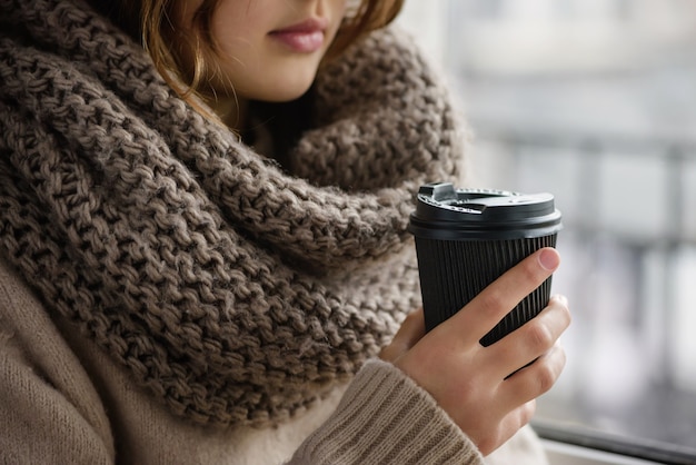 Meisje houdt een papieren beker met koffie.