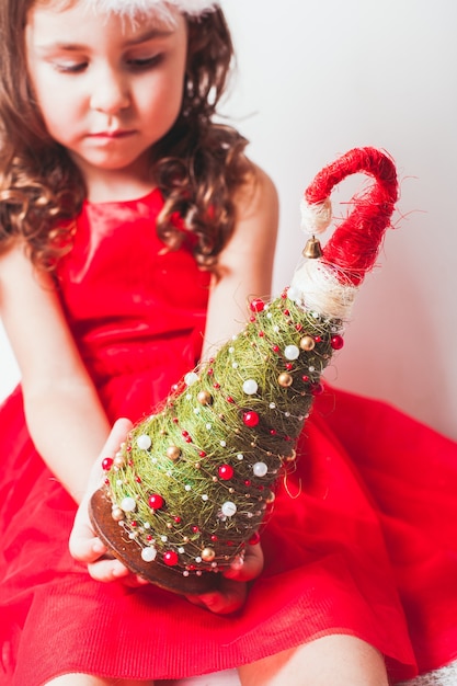 Meisje houdt handgemaakt decor in haar handen - Kerstboom van sisal en kralen