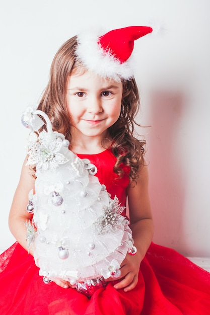 Meisje houdt in haar handen handgemaakt decor - kerstboom van zilveren lint