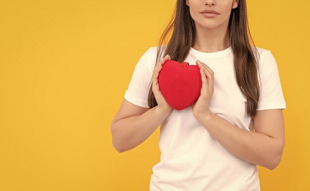 Meisje houdt rood hart in wit overhemd op gele achtergrond donatie