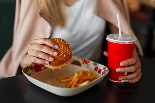 Meisje houdt van een hamburger, fastfood eten en cola drinken