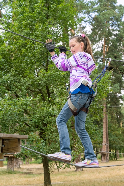 Meisje in avontuur dat hoog draadpark beklimt