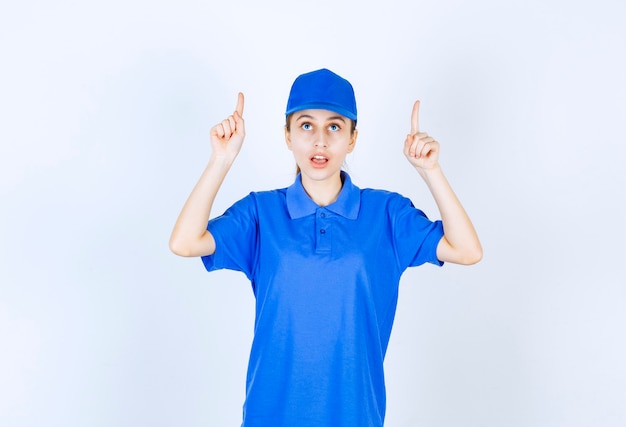 Meisje in blauw uniform wijzend op iets hierboven.