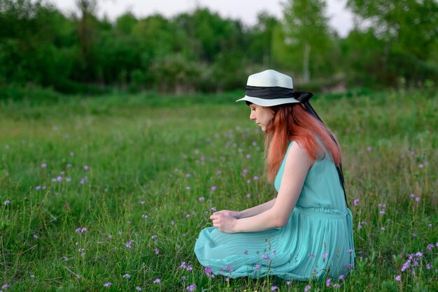 Meisje in blauwe jurk zittend in een veld met bloemen