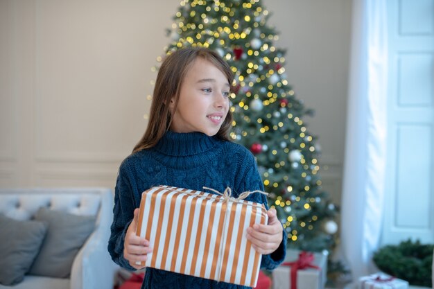 Meisje in blauwe trui glimlachen terwijl kerstcadeau