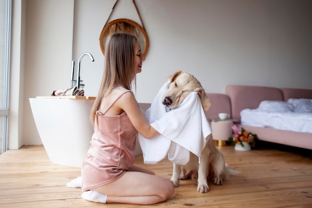 Meisje in de badkamer veegt haar hond af met een handdoek, een vrouw droogt een golden retriever af na het baden