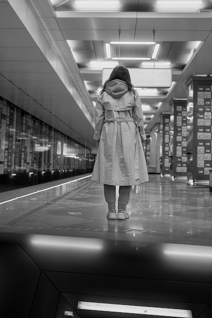 Foto meisje in een beige trenchcoat in de metro wachtend op de trein op het perron