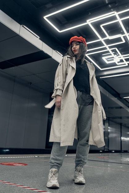 Meisje in een beige trenchcoat in de metro wachtend op de trein op het perron