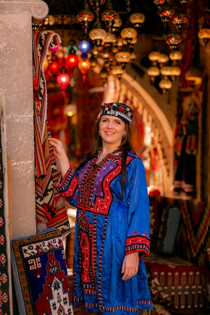 Meisje in een blauw Turks nationaal kostuum Gefotografeerd in een tapijtwinkel