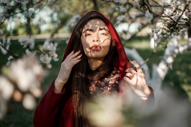 Meisje in een bloemrijke tuin in een kastanjebruine jas