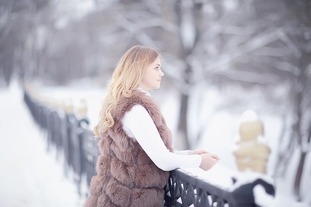 meisje in een bontvest loopt in de winter buiten / volwassen jong model in winterkleren bont